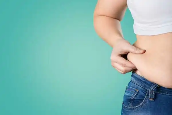 Image of woman pinching her love handles to show weight gain London